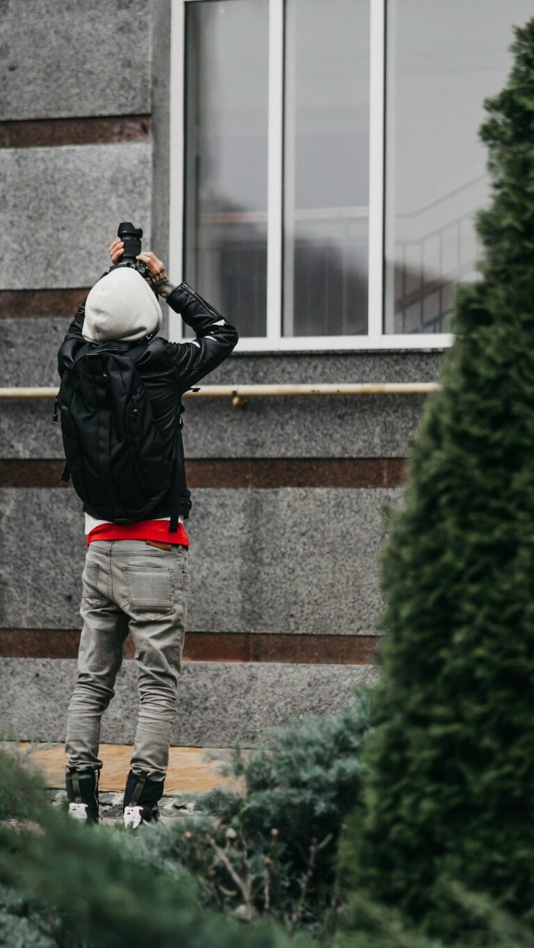 Homeowner examines a residential roof from the ground while a secured ladder rests nearby.